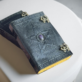 Decorative book with star design and purple gem on a white surface
